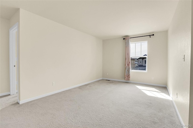 unfurnished room featuring light colored carpet and baseboards