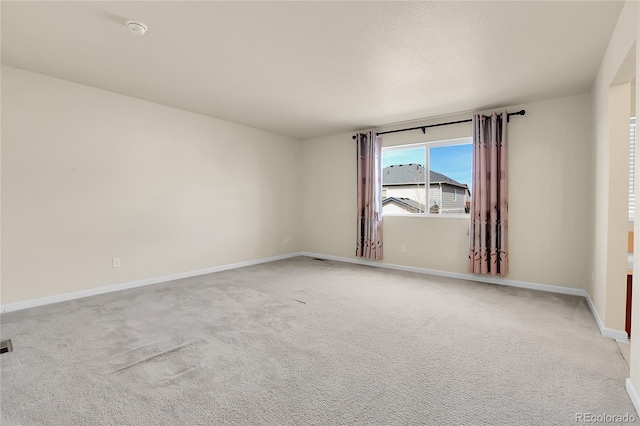 spare room featuring light colored carpet and baseboards
