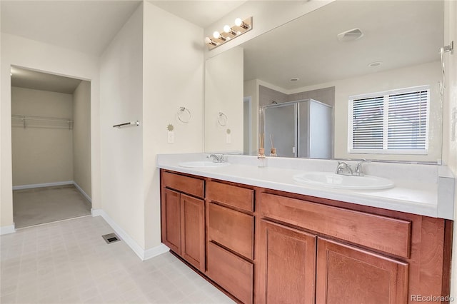 full bathroom with double vanity, visible vents, a shower stall, a sink, and a spacious closet