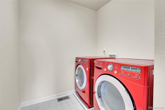 clothes washing area featuring baseboards, laundry area, visible vents, and washer and clothes dryer