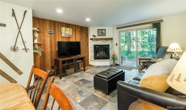 living room with a fireplace and wood walls