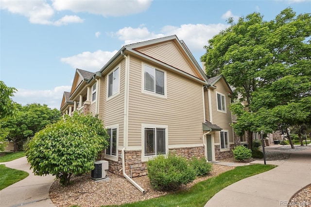 9692 W Coco Cir Unit 304, Littleton, CO 80128 - view of property exterior featuring stone siding and central AC