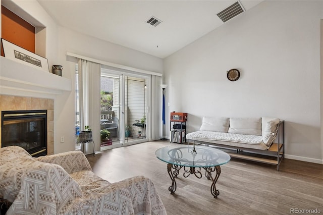 9692 W Coco Cir Unit 304, Littleton, CO 80128 - living area featuring wood finished floors, lofted ceiling, baseboards, and a tile fireplace