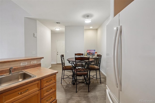 9692 W Coco Cir Unit 304, Littleton, CO 80128 - kitchen with freestanding refrigerator, a sink, baseboards, light countertops, and wood finished floors