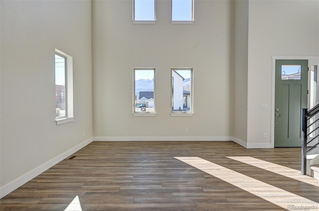 interior space featuring a towering ceiling and dark hardwood / wood-style floors