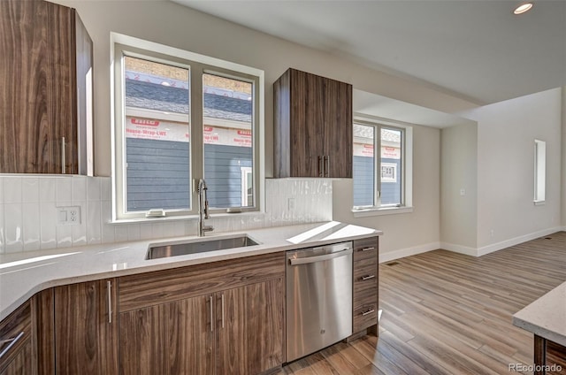 kitchen featuring tasteful backsplash, dishwasher, light hardwood / wood-style floors, and sink