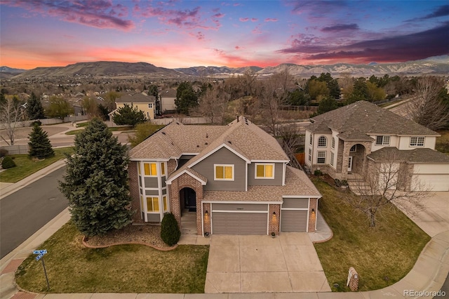 traditional-style house featuring a garage, a mountain view, concrete driveway, and brick siding