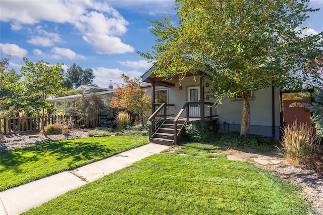view of front facade featuring stucco siding, fence, and a front lawn