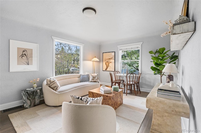 living room with baseboards, plenty of natural light, wood finished floors, and visible vents