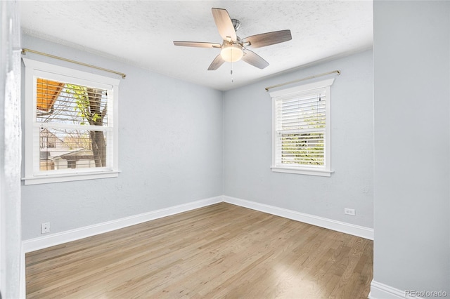 empty room featuring baseboards, a textured ceiling, wood finished floors, and a wealth of natural light