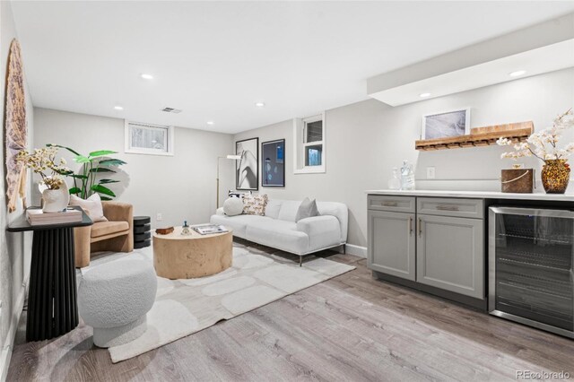 living area featuring beverage cooler, recessed lighting, a bar, and light wood finished floors