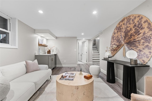 living room featuring visible vents, stairs, light wood-style floors, recessed lighting, and wet bar
