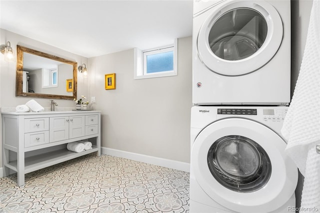 laundry area featuring baseboards, laundry area, a sink, and stacked washing maching and dryer