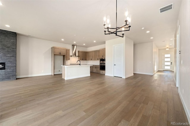 1724 Barefoot Dr, Windsor, CO 80550 - unfurnished living room featuring a chandelier, light wood-style flooring, recessed lighting, a stone fireplace, and baseboards