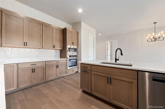 1724 Barefoot Dr, Windsor, CO 80550 - kitchen with appliances with stainless steel finishes, a sink, light wood-style flooring, tasteful backsplash, and light countertops