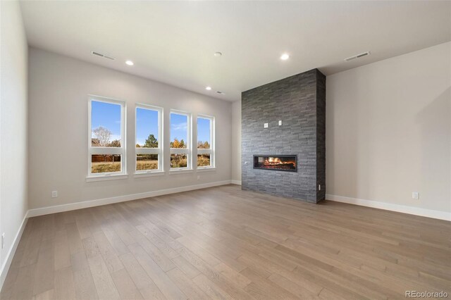 1724 Barefoot Dr, Windsor, CO 80550 - unfurnished living room with light wood-type flooring, a large fireplace, baseboards, and recessed lighting
