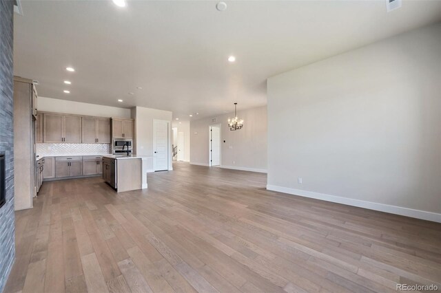 1724 Barefoot Dr, Windsor, CO 80550 - kitchen featuring open floor plan, a chandelier, light countertops, a glass covered fireplace, and stainless steel microwave