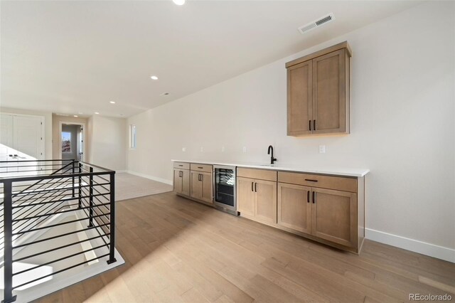 1724 Barefoot Dr, Windsor, CO 80550 - indoor wet bar featuring beverage cooler, baseboards, light wood finished floors, and recessed lighting