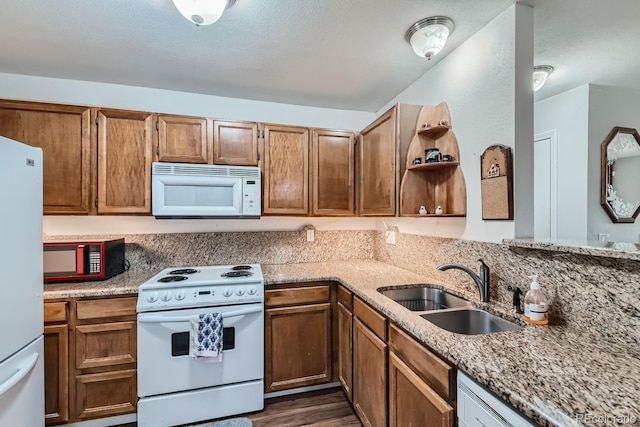 kitchen featuring light stone counters, white appliances, dark wood-type flooring, a sink, and open shelves