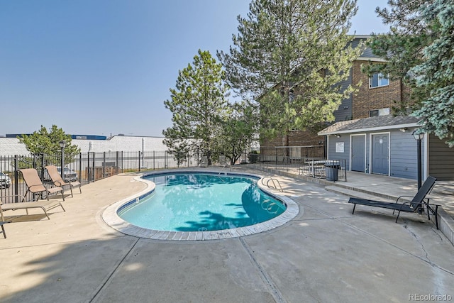 community pool with a patio area and fence