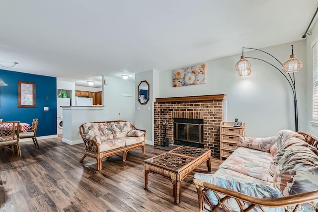 living room featuring a brick fireplace, wood finished floors, and baseboards