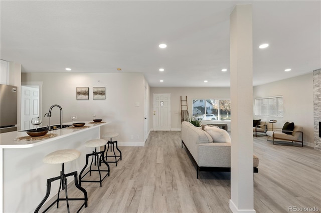 living room featuring recessed lighting, baseboards, and light wood finished floors