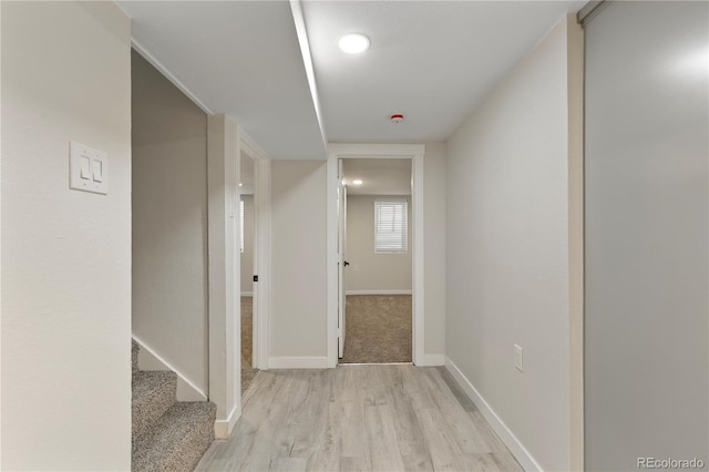 hallway featuring light wood-type flooring, stairway, and baseboards