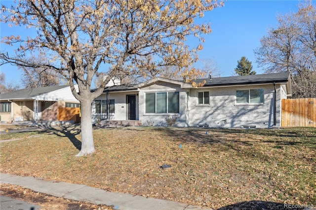 single story home featuring a front yard, brick siding, and fence