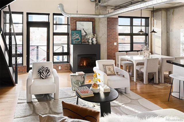 sitting room with brick wall, wood finished floors, and a glass covered fireplace