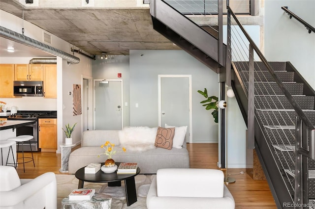 living area with a high ceiling, stairway, wood finished floors, and visible vents