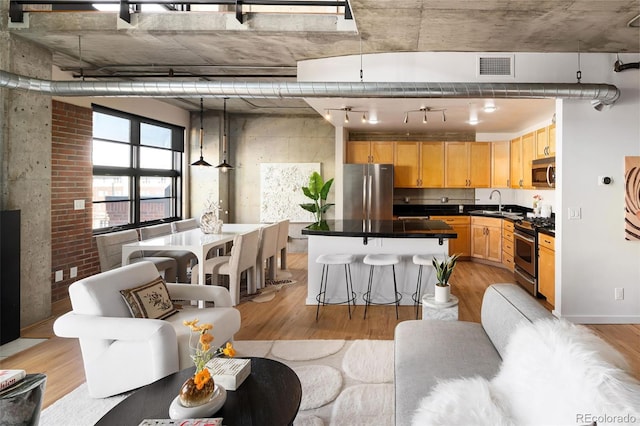 interior space with light wood finished floors, dark countertops, visible vents, light brown cabinetry, and appliances with stainless steel finishes