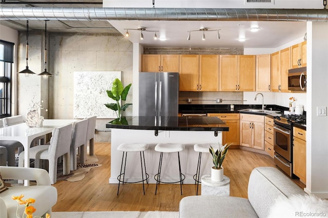 kitchen with stainless steel appliances, a breakfast bar, a sink, light wood-type flooring, and light brown cabinetry