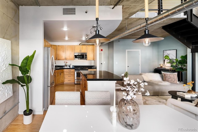 kitchen featuring visible vents, appliances with stainless steel finishes, open floor plan, light brown cabinetry, and light wood-type flooring