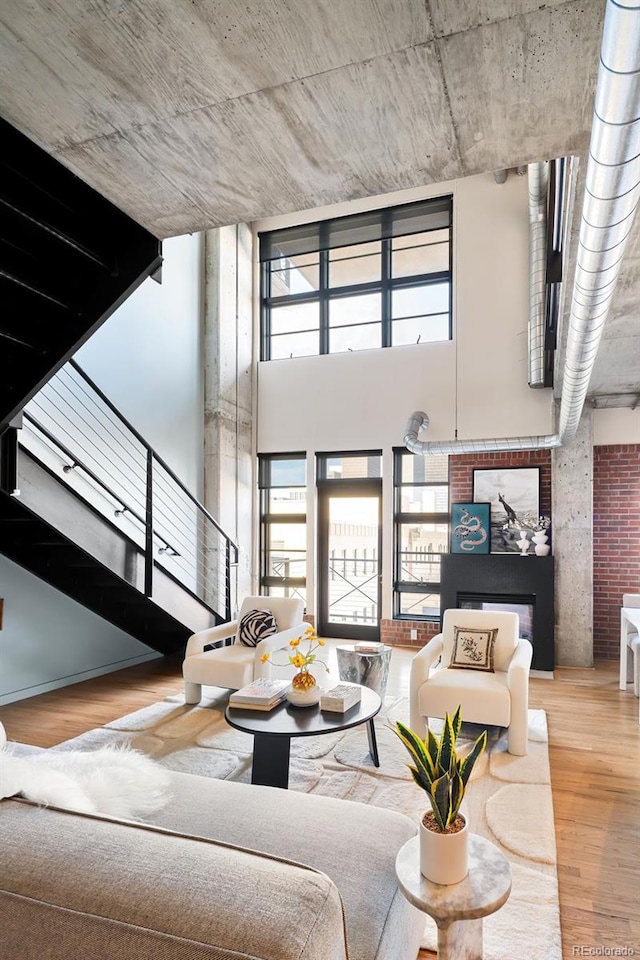 unfurnished living room with stairs, plenty of natural light, a towering ceiling, and wood finished floors