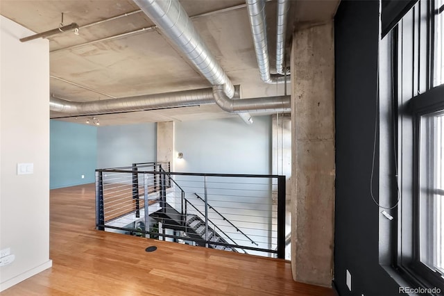 hallway with baseboards, an upstairs landing, and wood finished floors