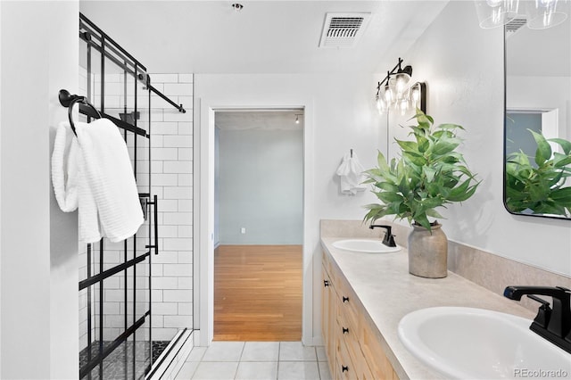 bathroom with a stall shower, tile patterned flooring, visible vents, and a sink