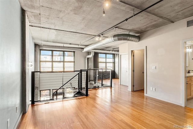 empty room featuring a sink, wood finished floors, visible vents, and baseboards