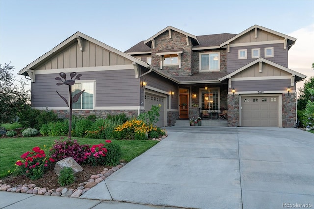 craftsman house featuring a garage, stone siding, driveway, and board and batten siding