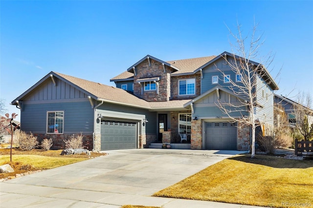 craftsman-style home featuring stone siding, a front yard, board and batten siding, and concrete driveway