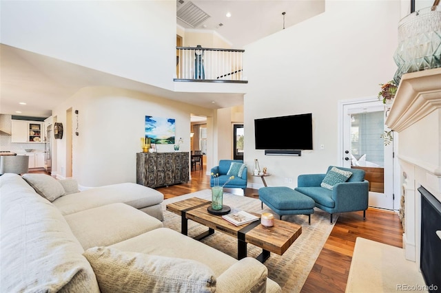 living room featuring a fireplace with flush hearth, recessed lighting, and wood finished floors