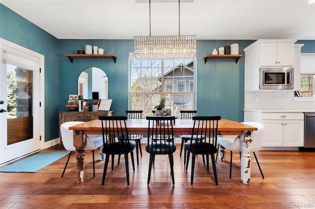 dining room with a chandelier, baseboards, and light wood-style floors