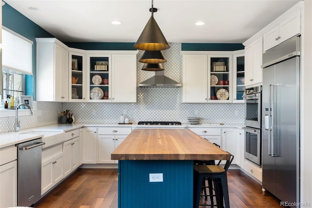 kitchen featuring stainless steel appliances, butcher block counters, a breakfast bar, a sink, and white cabinetry