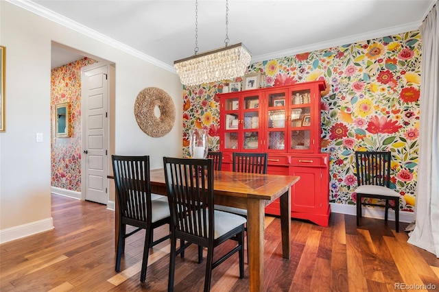 dining space with wallpapered walls, baseboards, wood finished floors, crown molding, and a chandelier