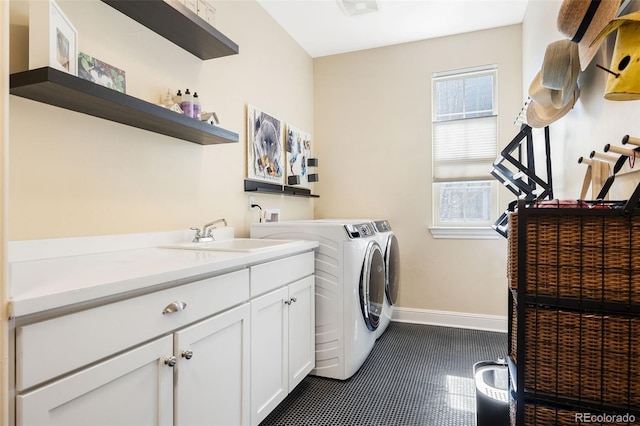 clothes washing area featuring washing machine and clothes dryer, cabinet space, a sink, dark tile patterned floors, and baseboards