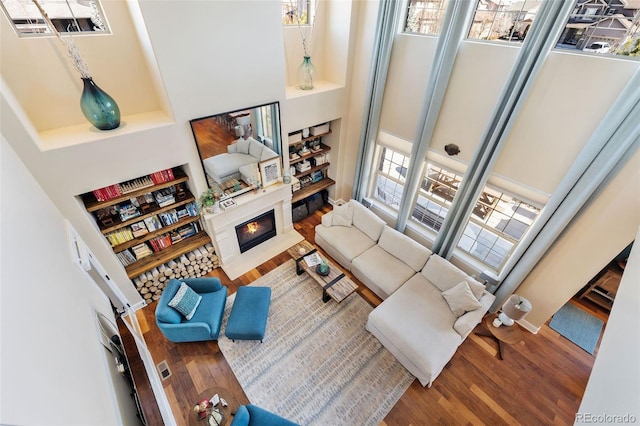 living room with a lit fireplace and wood finished floors