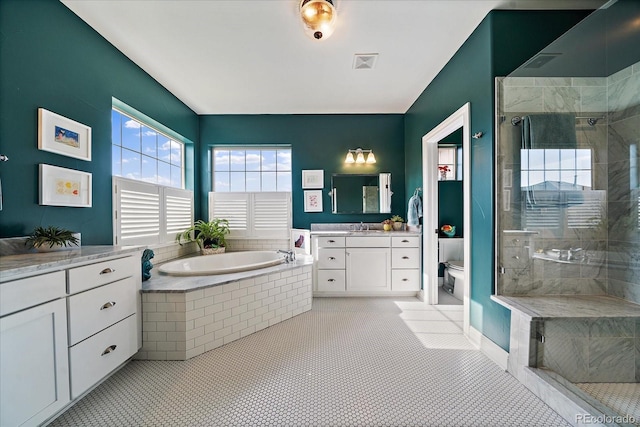 bathroom with a stall shower, visible vents, a garden tub, and vanity