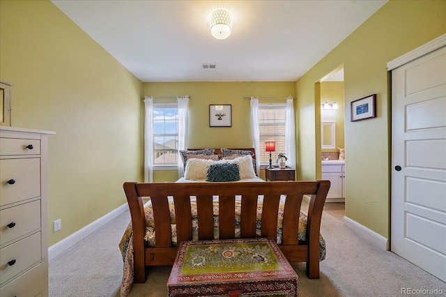 carpeted bedroom with ensuite bath, baseboards, and visible vents