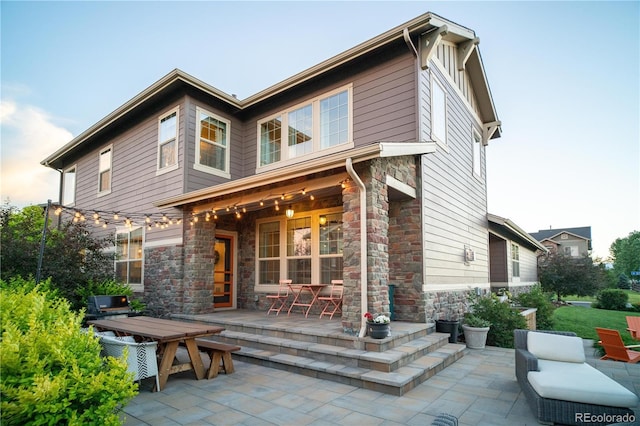 back of house featuring stone siding and a patio area