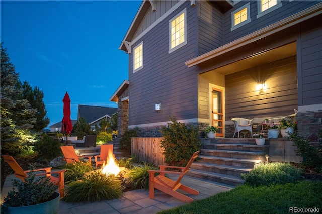 exterior space featuring covered porch, stone siding, board and batten siding, and a patio