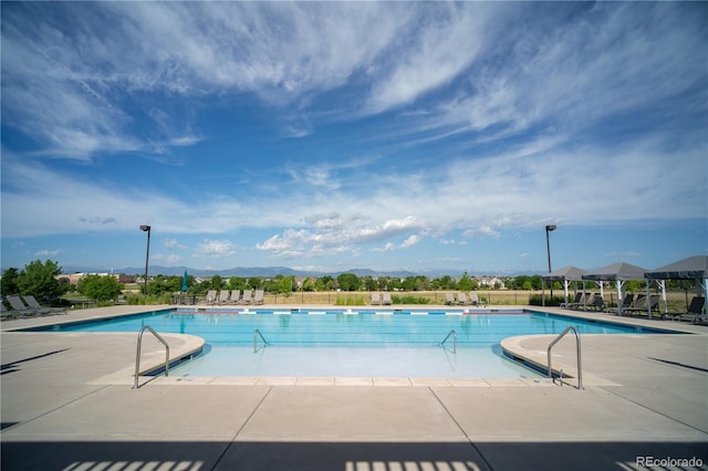 community pool with a patio area, fence, and a mountain view